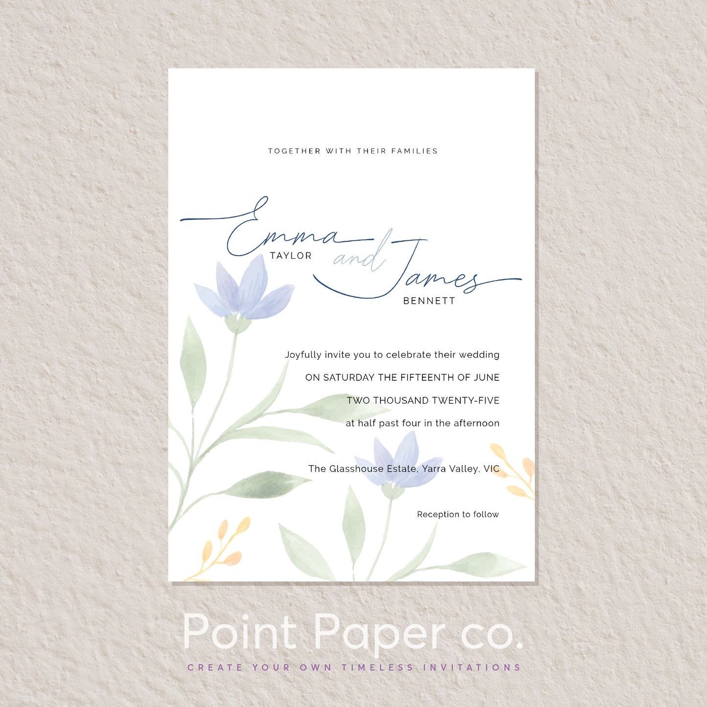 A vertical wedding invitation card with a white background, featuring elegant blue script names, floral illustrations in soft blue, green, and yellow, and formal invitation text. The card is centered on a textured light beige wall, with the brand name 'Point Paper co.