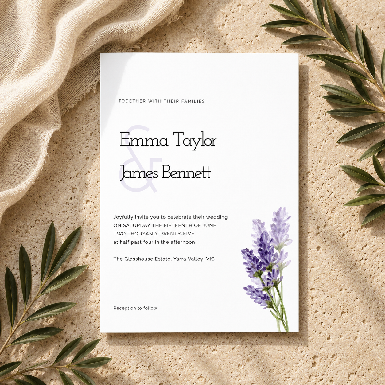 A square wedding invitation card with elegant black typography and a small purple floral illustration in the lower right, styled on a textured beige surface with draped cream fabric and green leaves around it.
