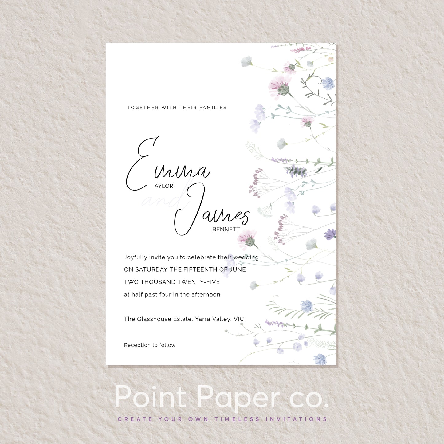 A vertical wedding invitation card with elegant black script names and floral watercolor accents in soft pink, lavender, and blue along the right edge, displayed on a textured light beige wall. The brand name 'Point Paper co.