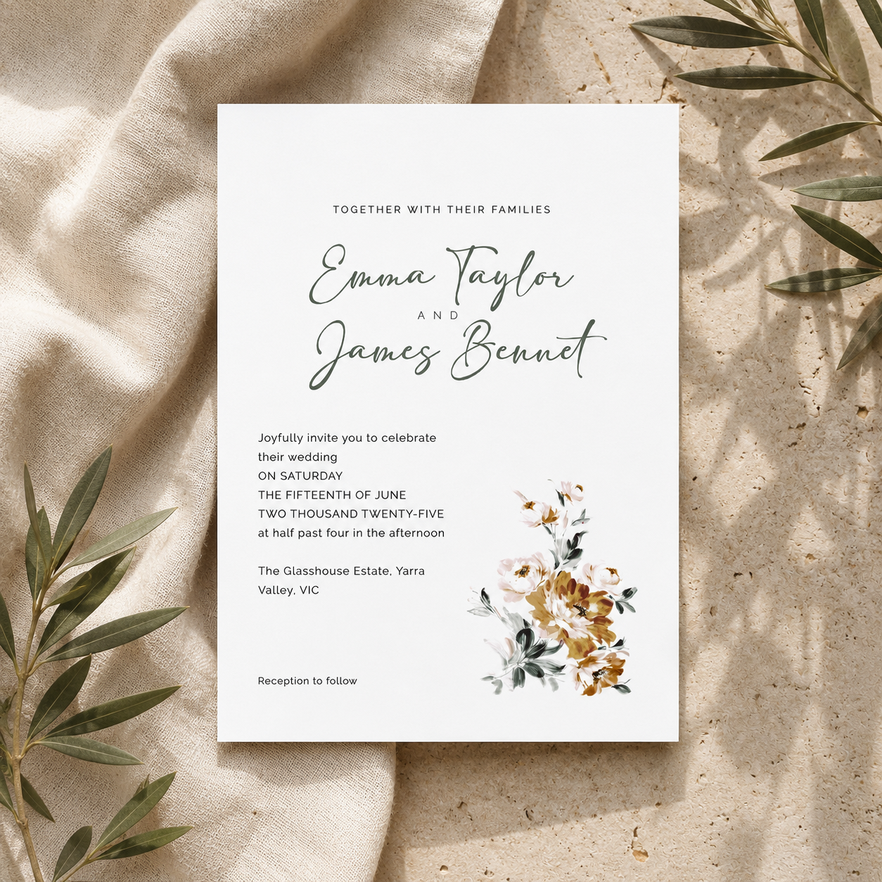 A wedding invitation card with elegant black script and floral watercolor accents, styled flat-lay on a textured beige fabric with olive leaves.