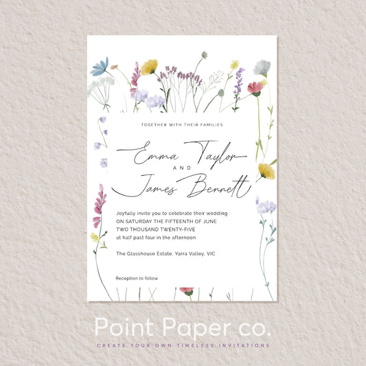 A floral wedding invitation card displayed on a textured light beige wall. The card features delicate watercolor illustrations of wildflowers in purple, yellow, pink, and green around elegant black script text reading 'Emma Taylor and James Bennett' and formal invitation copy.
