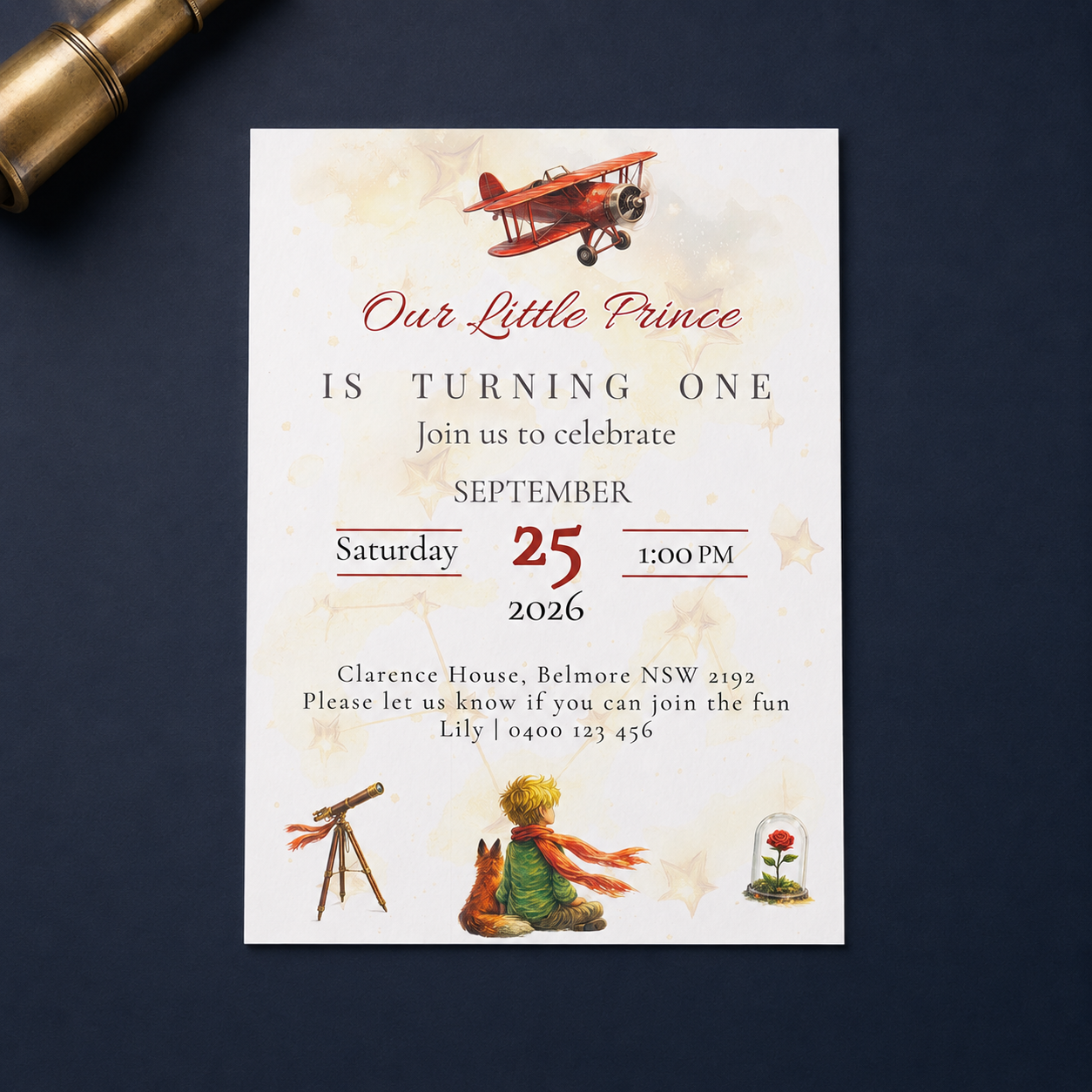 A vintage-style children's first birthday invitation card with a white background, featuring illustrations of a red biplane, a telescope, a teddy bear, and a small flower dome. The card is displayed flat on a dark navy blue surface next to a gold telescope prop.