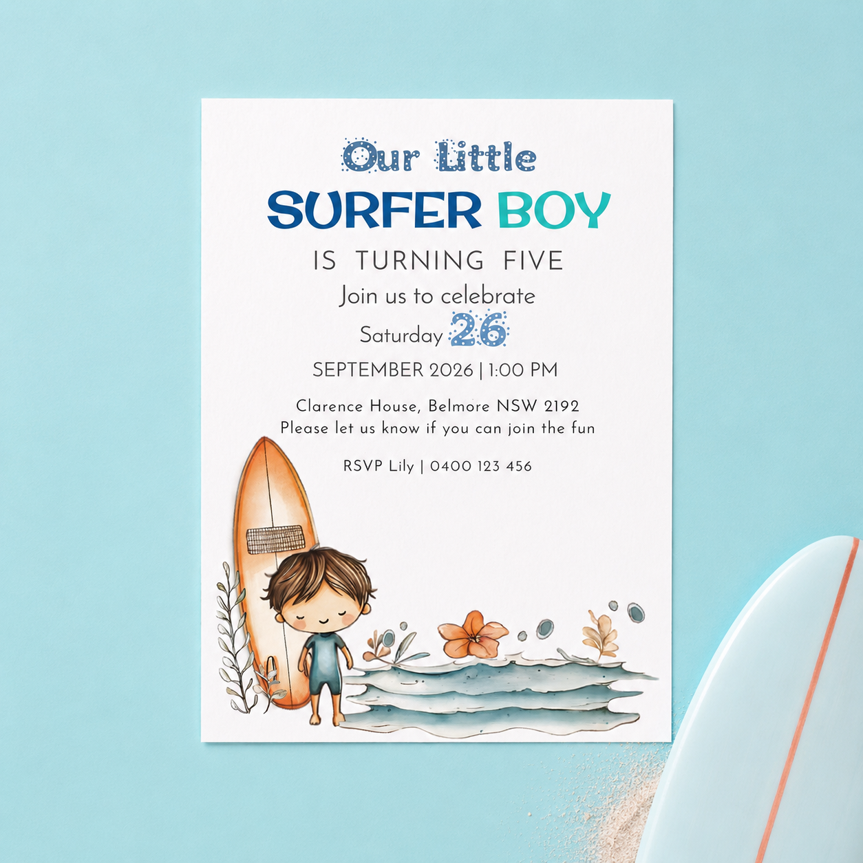 A square birthday invitation card for a boy named 'Our Little Surfer Boy' is displayed on a light blue background with a partial surfboard prop. The card features a white base with blue and teal text, and a watercolor illustration of a young boy standing on ocean waves next to an orange surfboard.